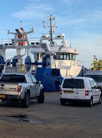 Een kotter in de haven van Urk met op de kade bedrijfswagens van KRIMPEX Coating Systems