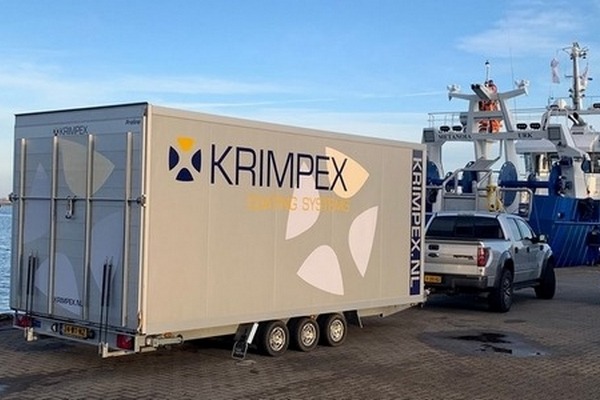 Een kotter in de haven van Urk met op de kade bedrijfswagens van KRIMPEX Coating Systems